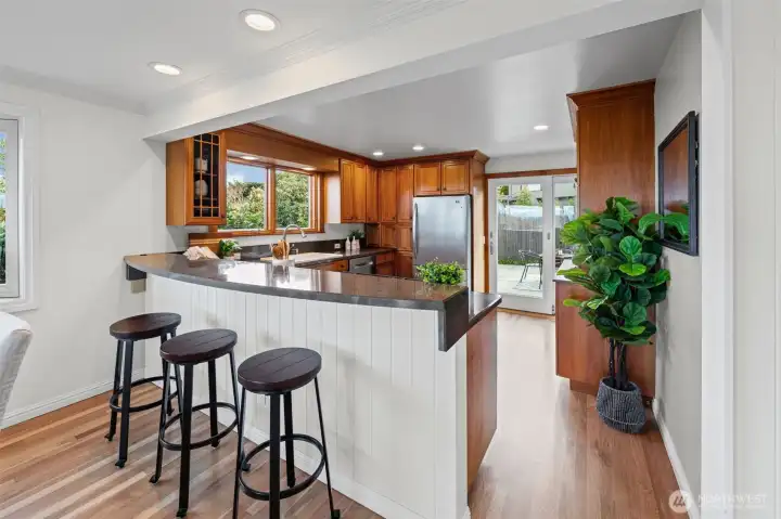 A spacious peninsula with bar seating anchors the kitchen, offering the perfect place to gather and connect. Rich cherry cabinetry, crown molding, and seamless flow to the patio create a functional and inviting layout.