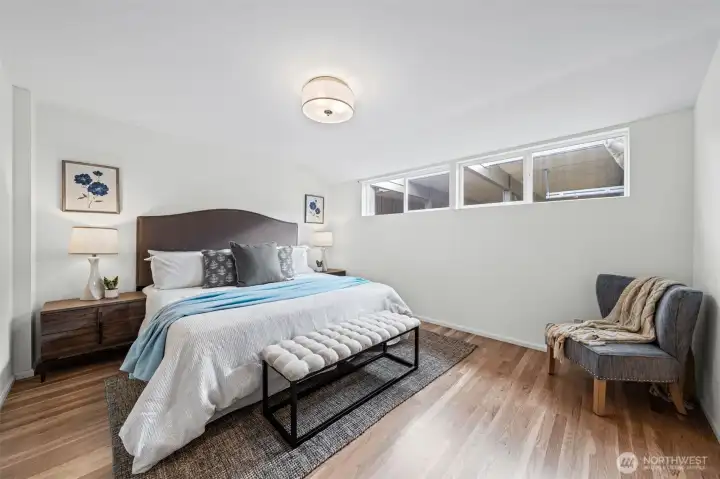 Welcome to the Primary Suite featuring hardwood floors, clean lines, and soft natural light. A wide layout offers room for additional seating while maintaining a calm, open feel.