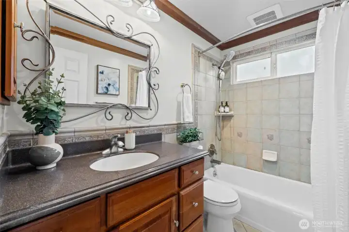 Full bathroom with tile tub/shower surround, quartz vanity, and ample counter space. Functional layout with clean finishes supports everyday living with ease.