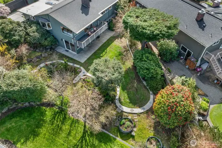 Aerial perspective showcasing the home’s private setting, mature landscaping, and thoughtfully designed yard with pathways, garden beds, and inviting outdoor spaces.