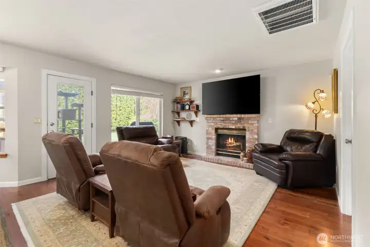 Cozy living room centered around a gas fireplace, with seamless access to the backyard for indoor-outdoor living.
