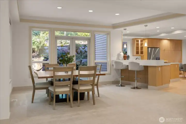 Dining area filled with natural light and tranquil garden views, with easy access to kitchen bar seating for casual gatherings.