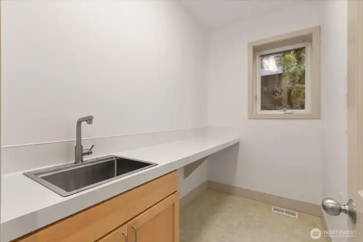 Dedicated main-level utility room with sink, extended counter space, and natural light—ideal for projects, storage, or additional prep space.