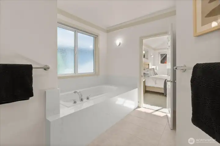 Relax in the soaking tub with new quartz surround, set beneath a large window for natural light. Select windows scheduled for replacement, and a new glass shower door to be installed—offering added value and peace of mind.