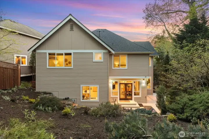 Inviting rear elevation with seamless indoor-outdoor flow to a private patio setting surrounded by mature landscaping.