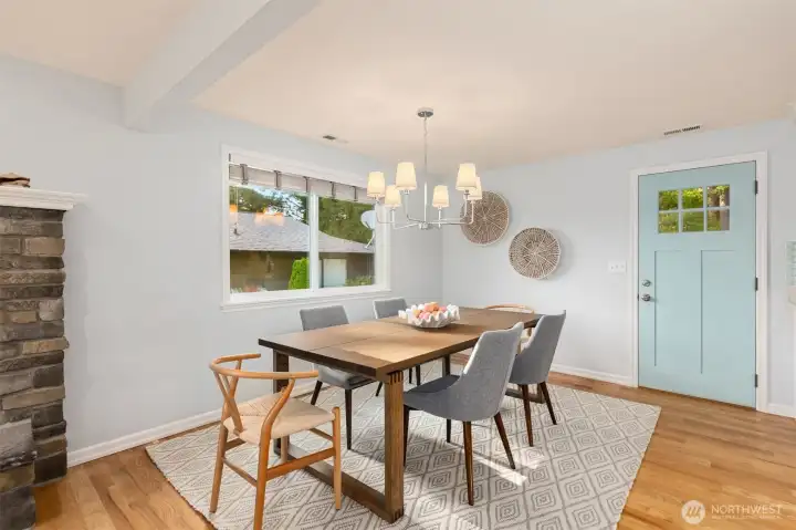 Inviting dining area featuring a stylish chandelier, hardwood floors, and a cozy stone fireplace. Inviting dining area featuring a stylish chandelier, hardwood floors, and a cozy stone fireplace.