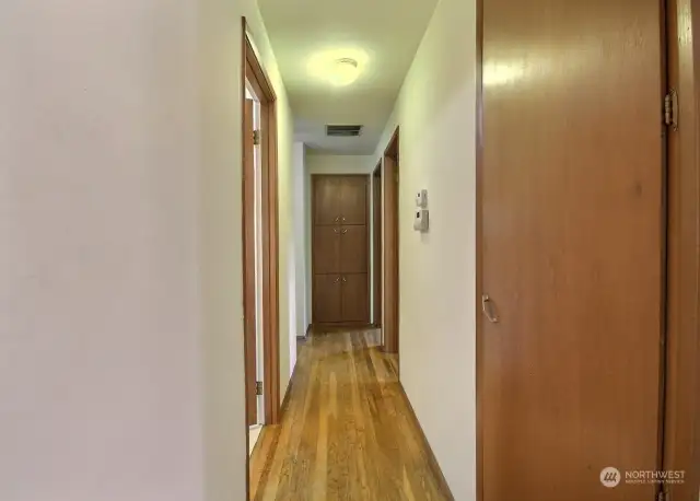 Hallway to the 4 bedrooms features  n original built-in storage cabinet.  The door to the full bath is on the left.