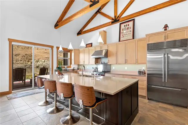 View 4 of welcoming kitchen with oversized quartz island and sliding glass doors leading to the outdoor living area.