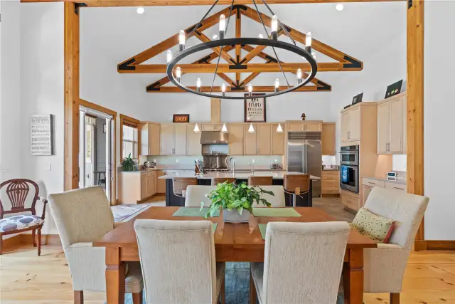 View 1 of the Dining Room with soaring ceilings, exposed wood beams, wide plank wood floors, stone fireplace and glass sliding doors leading to the outdoor living area.