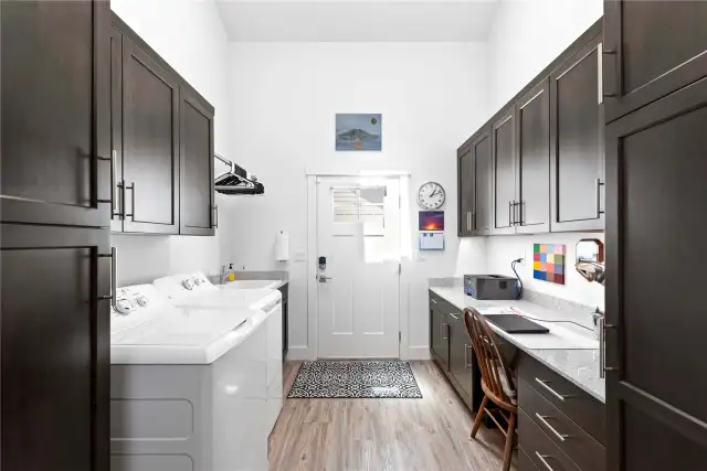 Laundry/utility room with custom cabinetry, home office and exterior door leading to side yard w/ outdoor shower and graveled boat and trailer storage area.