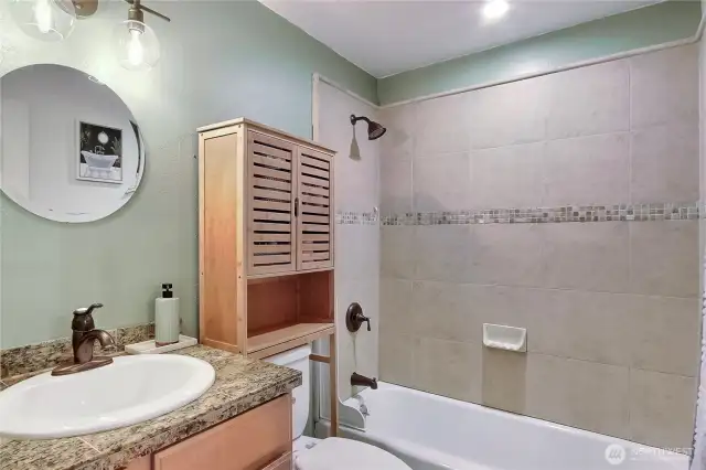 Full bath with matching granite countertops and a beautiful tiled tub.