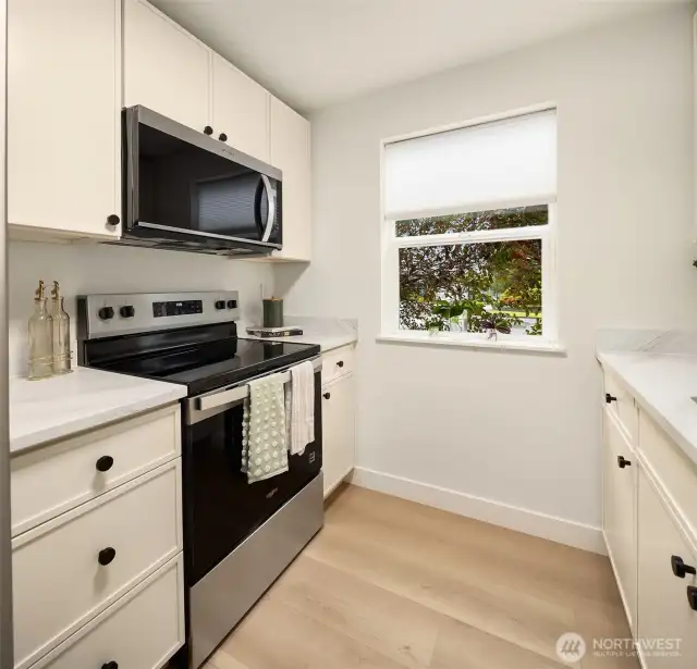 Cream thin shaker cabinets with quartz countertops and new appliances