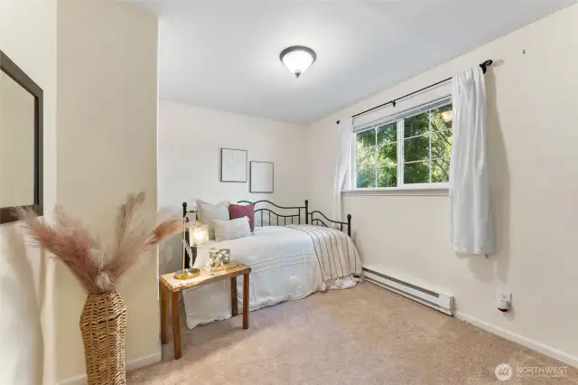 Main floor bedroom 1. Bright bedroom with natural light, soft carpeting, and space for a full or queen-sized bed.
