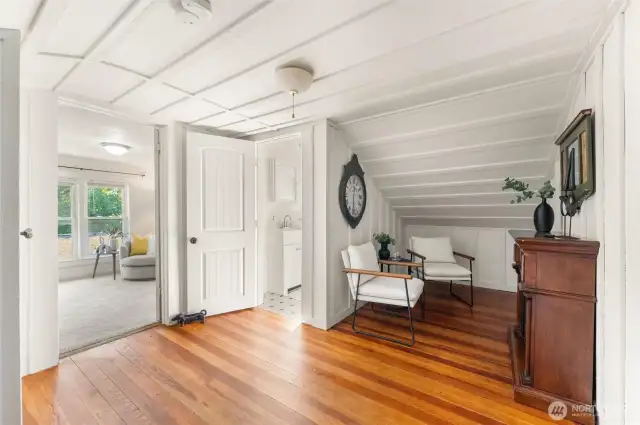 Charming upstairs landing with hardwood floors and natural light, offering access to two bedrooms and a full bathroom.