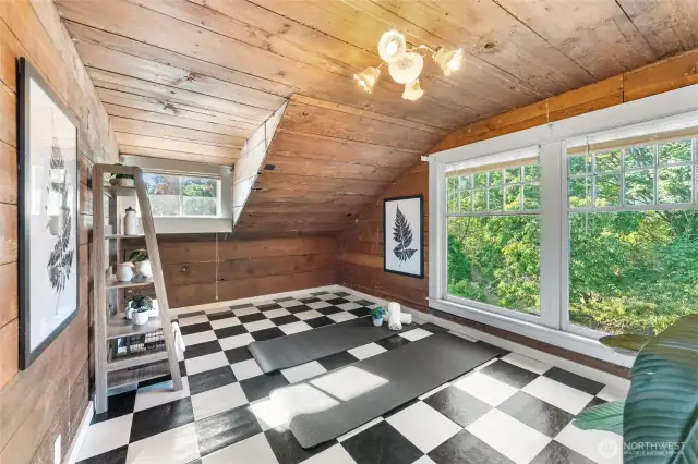 Spacious upstairs bedroom #5 with wood-paneled walls, large windows with treetop views, and versatile space perfect for a bedroom, yoga studio, or reading room.