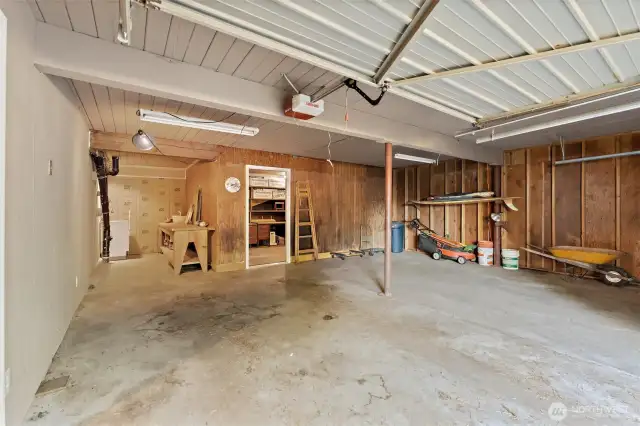 Spacious two-car garage with concrete floors, built-in workbench, and direct access to the basement shop for projects and storage.