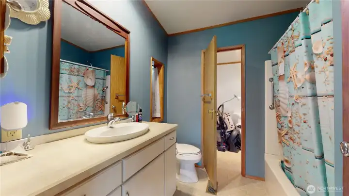 Another view of the primary bathroom with door leading to the mudroom beyond.