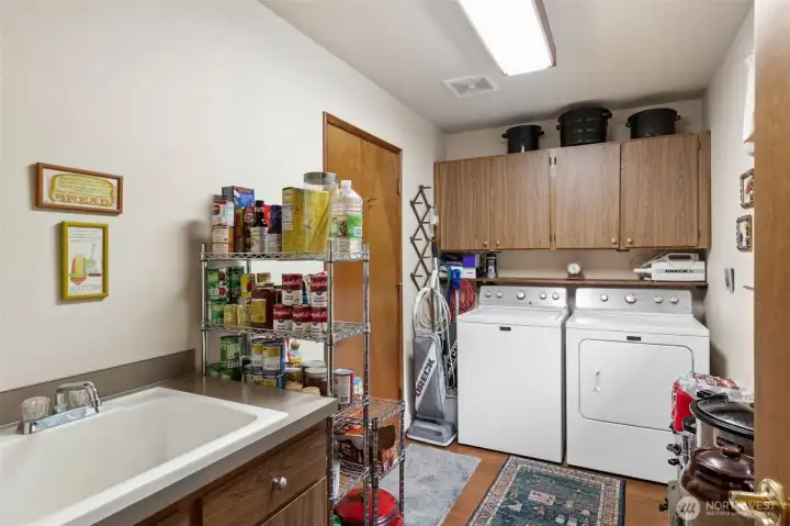 Laundry room (just off the kitchen) with a deep sink is spacious enough for plenty of storage. Door to the left is the entry to the garage.