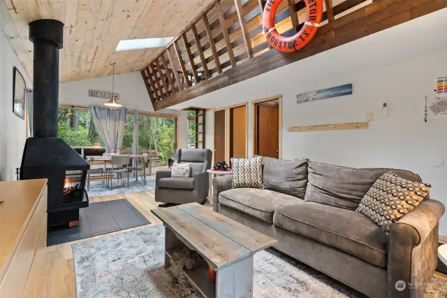 Great room with loft above showcases new wood-lined ceiling with skylight!