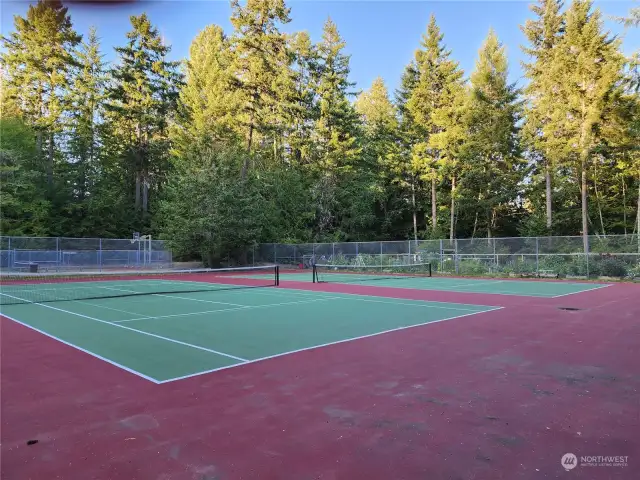 Double tennis courts near clubhouse w/community gardens beyond