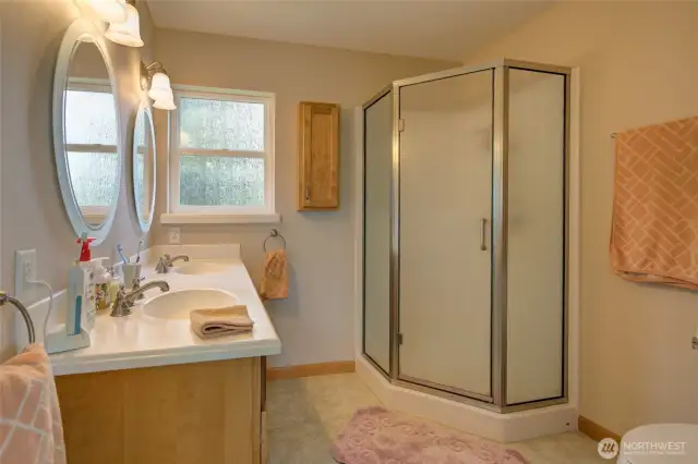 Primary bathroom has a dual vanity and step in shower.