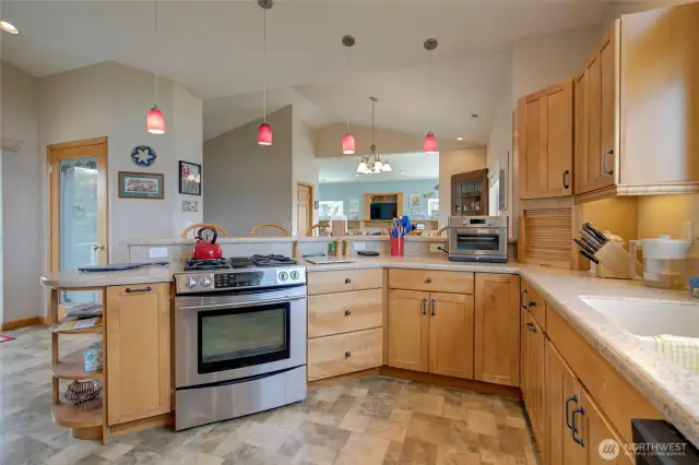 Look over the propane cooktop and peninsula bar seating towards the pantry, dining, and living areas.
