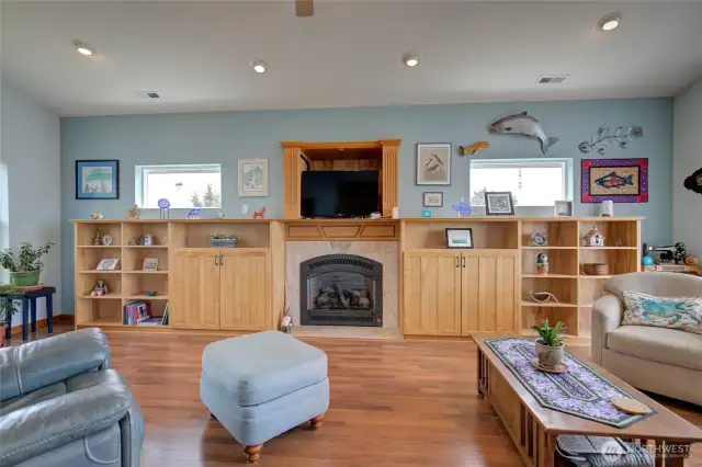 Exiting the dining area, the living room opens up to a centrally located propane fireplace surrounded by custom cabinetry, and amazing three pane windows to the East, South and West!