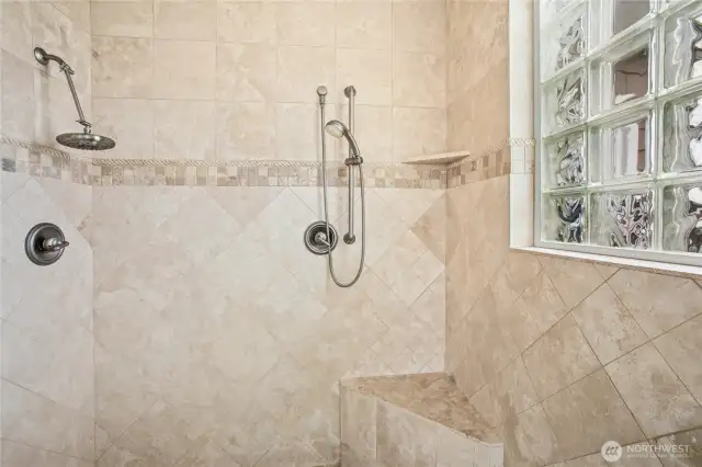 The spacious primary suite shower has dual shower heads.