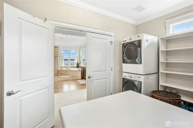 The primary walk-in closet with French doors has a convenient, full-size washer and dryer. No need to carry baskets down stairs. Clerestory windows provide natural light.