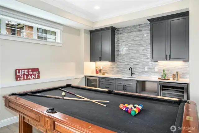 This kitchenette was designed with entertaining in mind. Note: cabinets for storage, sink with tile backsplash, small refrigerator and wine frig. A microwave has been added since this photo was taken. Clerestory windows ensure natural light. Crown molding ties this room in with the rest of the home.