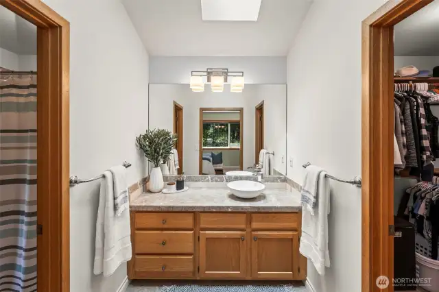 Primary Bathroom with a statement vessel sink, walk-in closet and bright skylight.