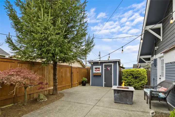 Your back yard oasis! Mature landscaping large concrete patio area and two storage sheds!