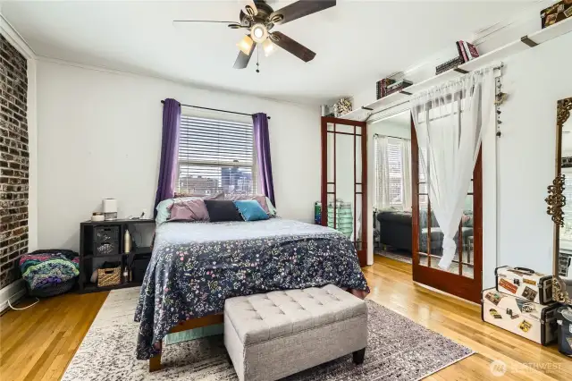 Truly spacious bedroom with French doors, views of the city, and gorgeous exposed brick. Don't miss the walk in closet with custom shelving.