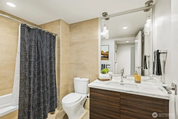 Spacious bath with quartz counters, modern tilework, and European-style cabinetry.