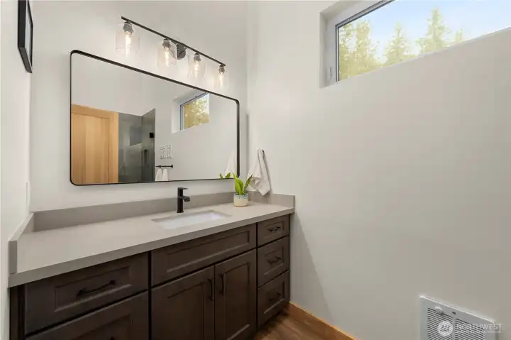 Primary bathroom features a quartz countertop vanity and an oversized high window that fills the space with natural light.