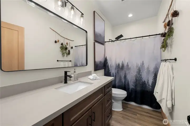 Even the spacious guest bathroom feels luxurious with sleek quartz countertop vanity and a shower bathtub combo with rainfall shower head and sprayer.