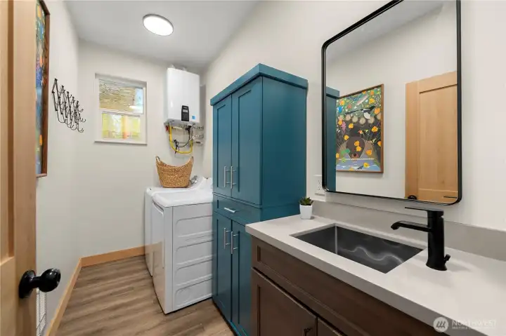 Convenient laundry/utility room houses the tankless propane water heater for instant hot water, with additional storage cabinets added in 2025.