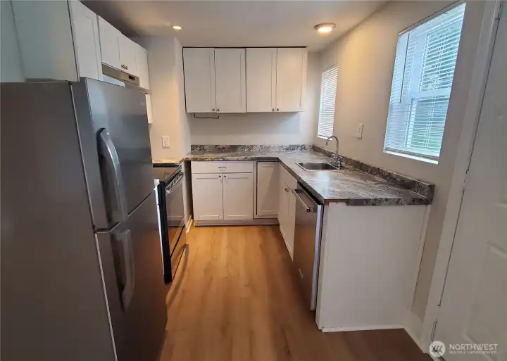 Unit 4 kitchen with newer appliances, cabinets, countertop, and LVP flooring. (Previous leasing photos).