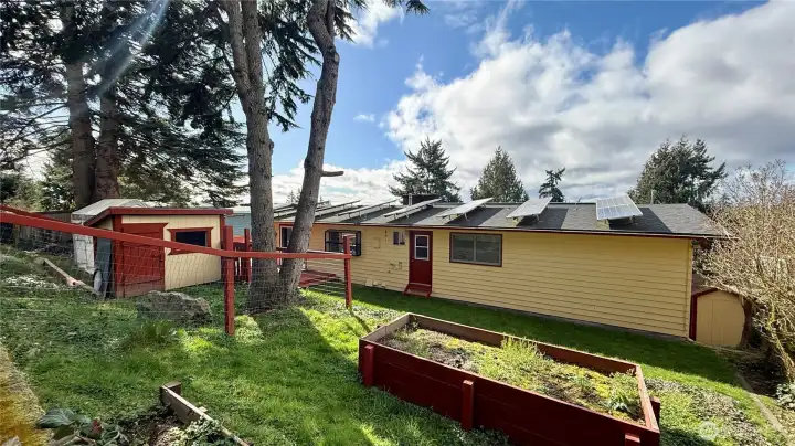 Energy-efficient home featuring 33 solar panels and double windows, chicken coop wood shed, raised garden beds plus older greenhouse.