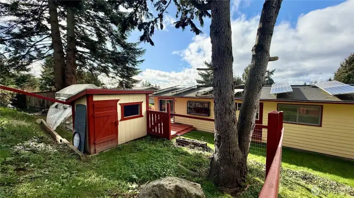 Energy-efficient home featuring 33 solar panels and double windows, chicken coop wood shed, raised garden beds plus older greenhouse.
