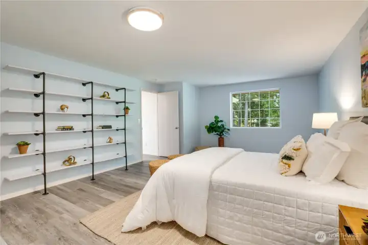 The primary bedroom is finished with custom shelving, updated lighting, and vinyl plank flooring. The primary bedroom is finished with custom shelving, updated lighting, and vinyl plank flooring.