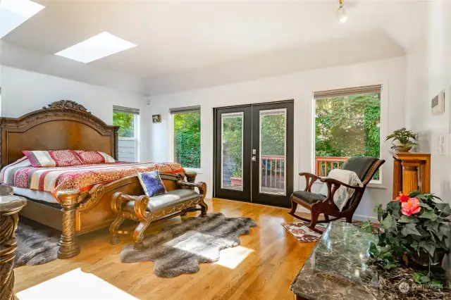 Large primary bedroom with custom fireplace and french doors leading to the deck.