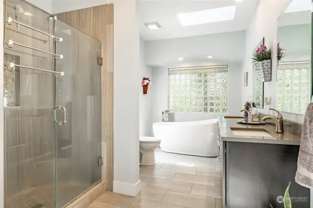 Bathroom attached to primary bedroom has soaking tub, walk-in shower, skylight, and walk-in closet.