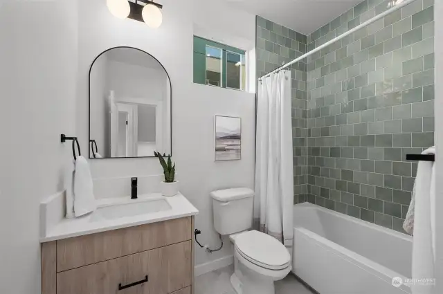 A sleek and modern bathroom featuring a green tile backsplash, elegant vanity, and natural light for a spa-like experience in the comfort of your own home.