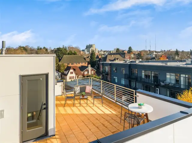Expansive rooftop deck with ample seating, offering breathtaking city and neighborhood views.
