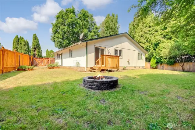Backyard looking at the home with fire pit and stairs to dining room.