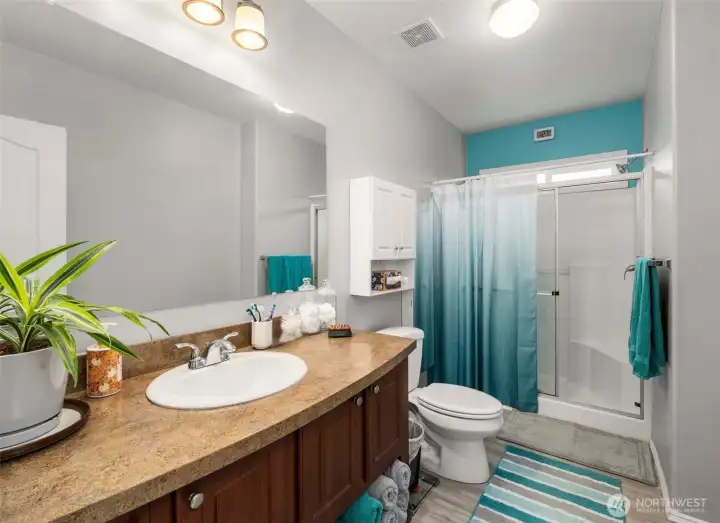 The primary bathroom feels bright and functional, with a spacious vanity and an easy-to-use walk-in shower w/molded seating.