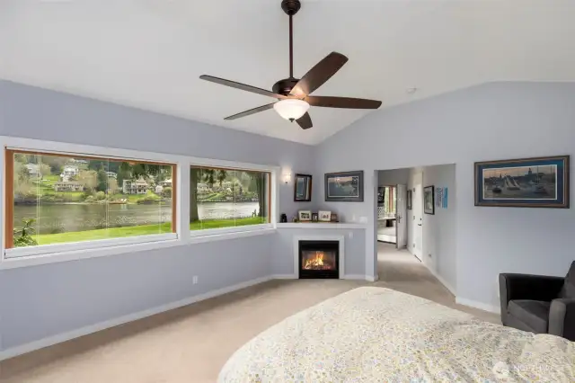 Unwind in the master bedroom featuring a cozy fireplace and stunning water views