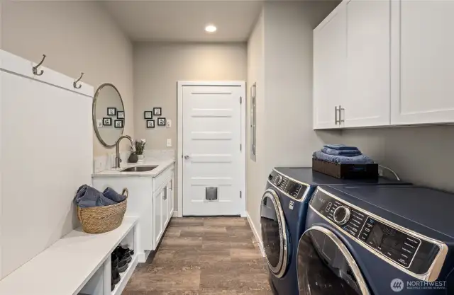 Utility room and hall closet with a deep sink and washer/dryer leading to the garage