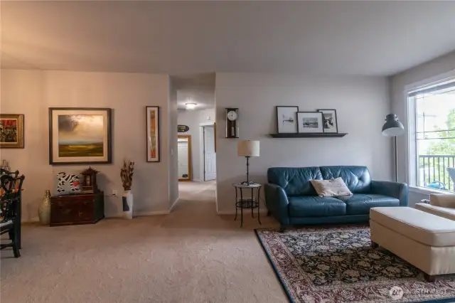 Bright and inviting open floor plan featuring plush wall-to-wall carpeting throughout. The seamless layout creates a spacious flow perfect for both relaxing and entertaining. Large windows enhance the natural light, highlighting the comfortable design and modern appeal.